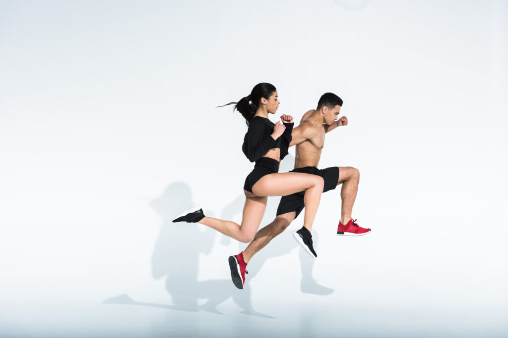 side view of sportive multicultural woman and man in sportswear and sneaker running on white side view of sportive multicultural woman and man in sportswear and sneaker running on white